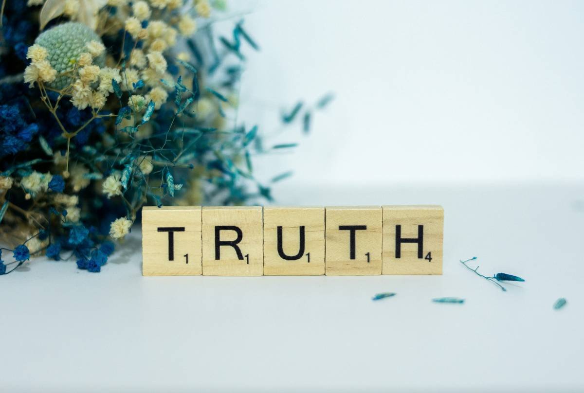 a wooden block spelling truth next to a bouquet of flowers